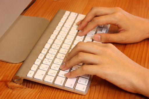 Macのキーボードを打つ女性の指